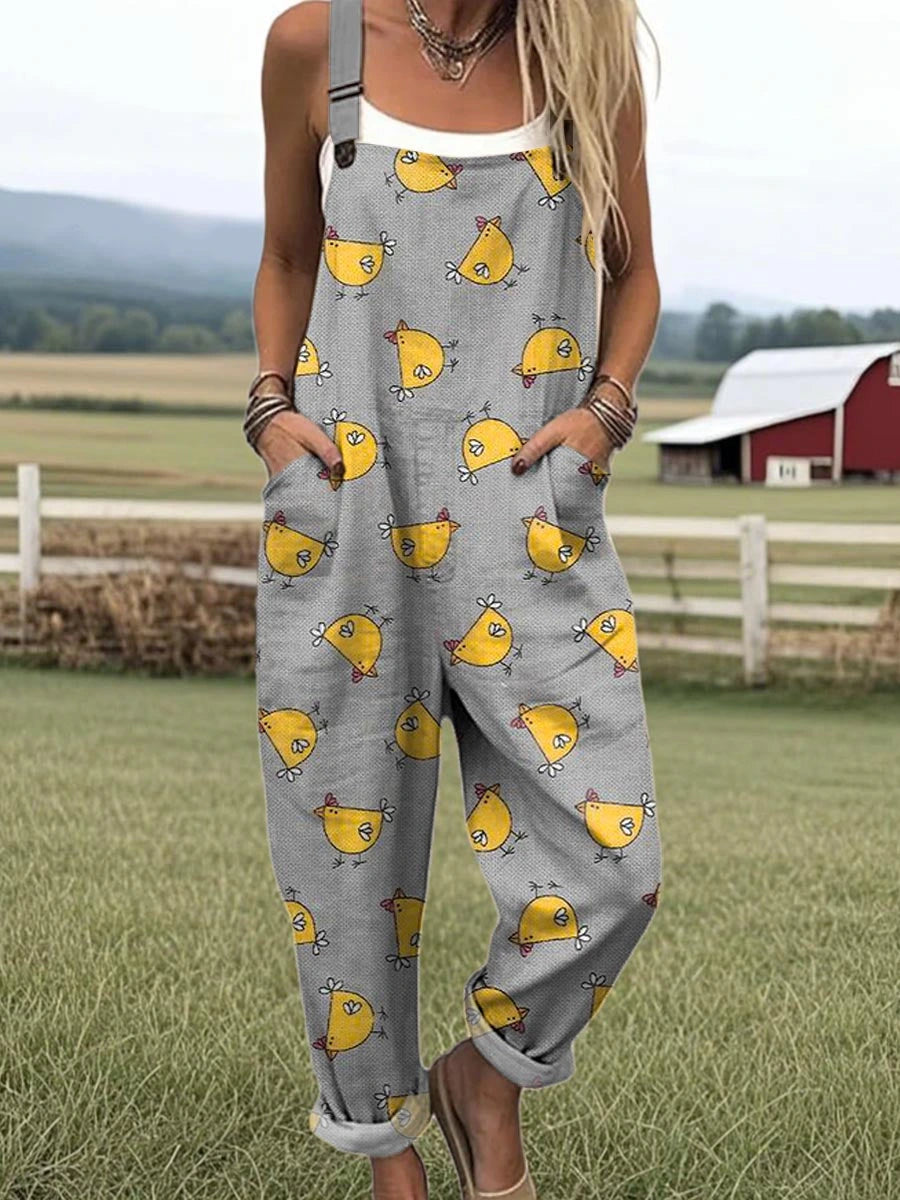 Woman wearing a gray chick-print short-sleeve jumpsuit standing in a farm field near a red barn