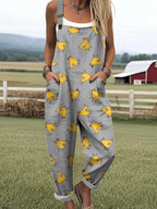 Woman wearing a gray chick-print short-sleeve jumpsuit standing in a farm field near a red barn