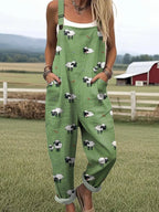 Woman wearing a green jumpsuit with a white sheep print standing in a farm field near a red barn