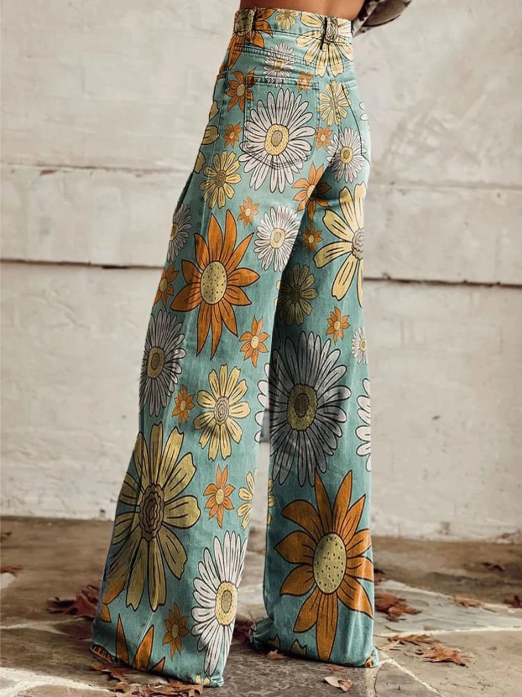 Close-up of teal palazzo pants with a yellow and orange daisy print, back view