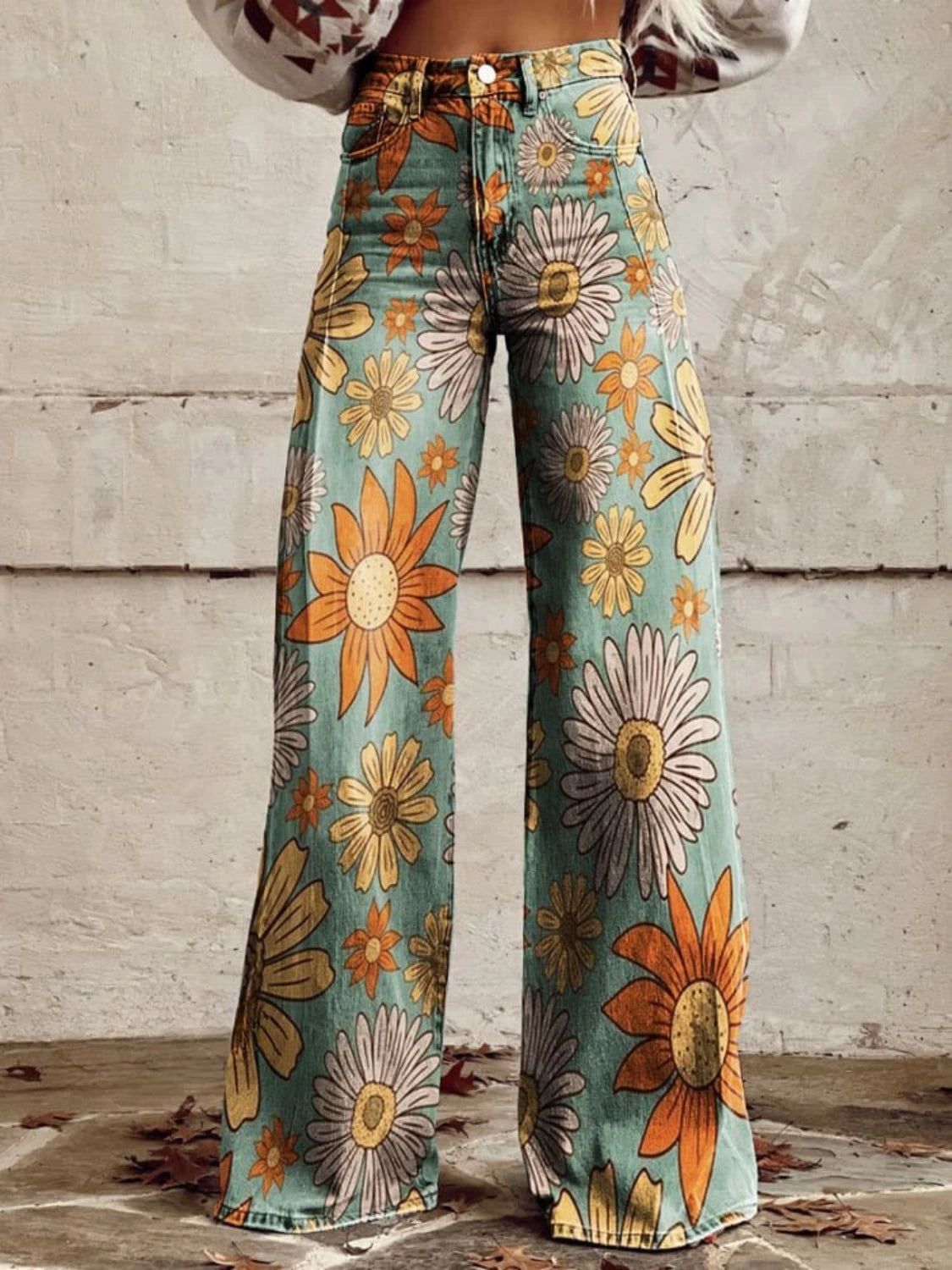 Close-up of teal palazzo pants with a yellow and orange daisy print, front view detail