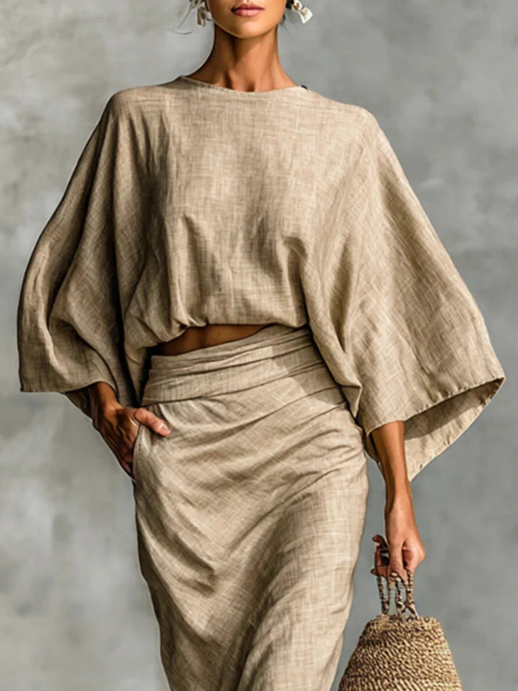 Woman wearing a khaki two-piece coordinating outfit, close-up front view with a straw bag