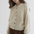 Woman wearing a cream button-up collared sweater, front view in a studio setting