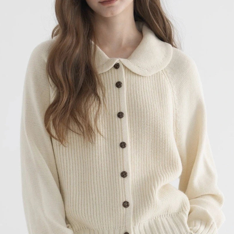 Woman wearing a cream button-up collared sweater, alternate pose in a studio setting