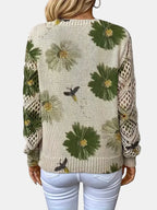 Woman wearing a green floral v-neck long sleeve sweater in a lifestyle setting, seated pose