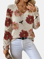 Woman wearing a red floral v-neck long sleeve sweater in an outdoor setting, walking pose
