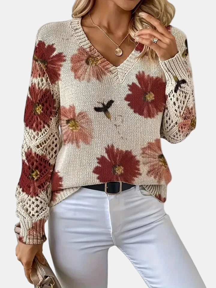 Woman wearing a red floral v-neck long sleeve sweater in an outdoor setting, walking pose