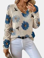 Woman wearing a blue floral v-neck long sleeve sweater, side profile in an outdoor setting