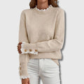 Woman wearing an apricot lace trim round neck long sleeve sweater in a studio setting