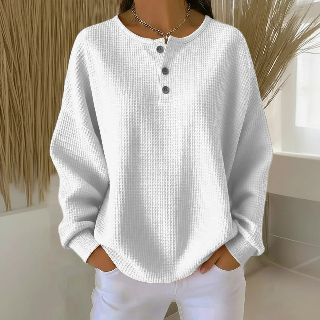 Woman wearing a white long sleeve waffle knit sweater in a studio setting
