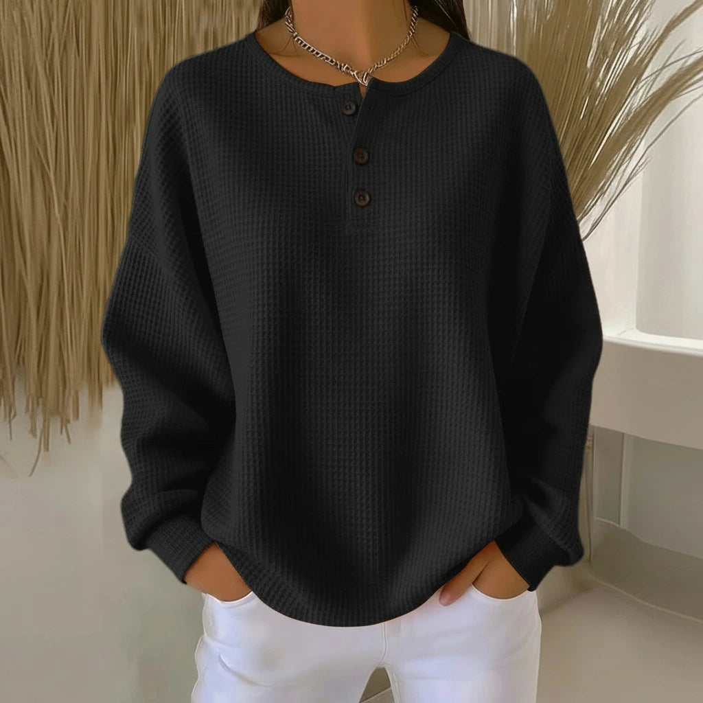 Woman wearing a black long sleeve waffle knit sweater in a studio setting