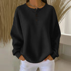 Woman wearing a black long sleeve waffle knit sweater in a studio setting