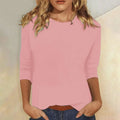 Woman wearing a pink crew neck three-quarter sleeve top in a studio setting