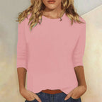Woman wearing a pink crew neck three-quarter sleeve top in a studio setting