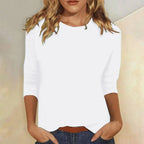 Woman wearing a white crew neck three-quarter sleeve top in a studio setting