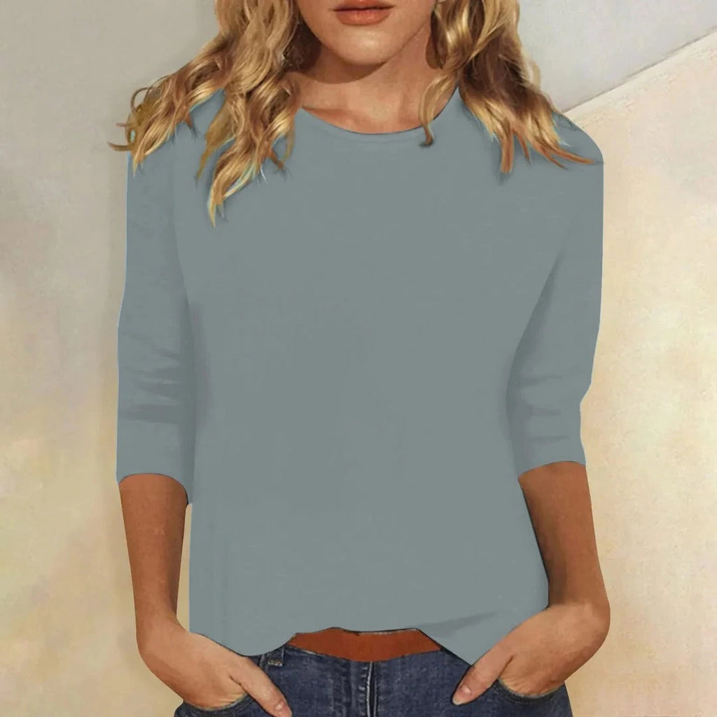 Woman wearing a blue crew neck three-quarter sleeve top in a studio setting