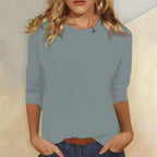 Woman wearing a blue crew neck three-quarter sleeve top in a studio setting