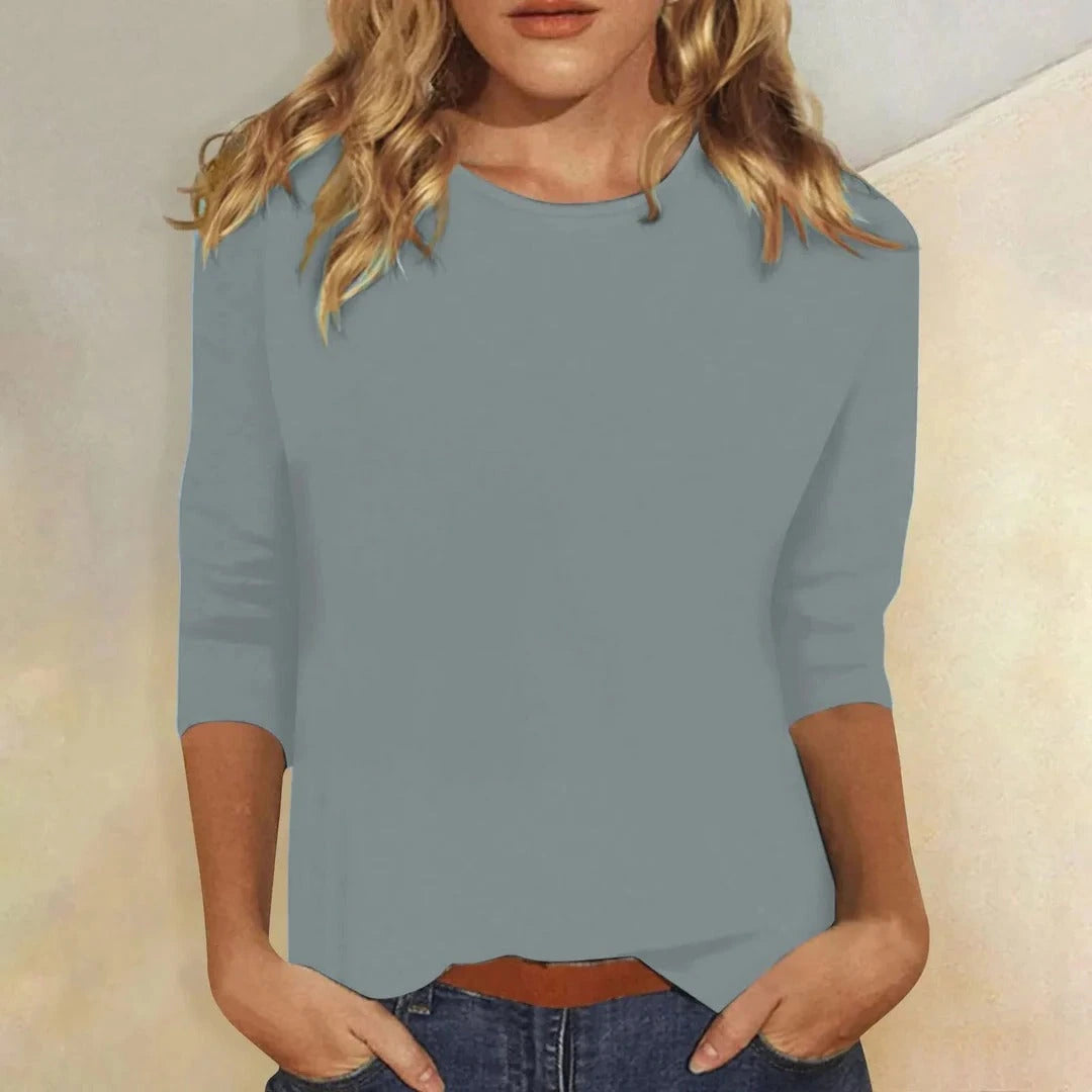Woman wearing a blue crew neck three-quarter sleeve top in a studio setting