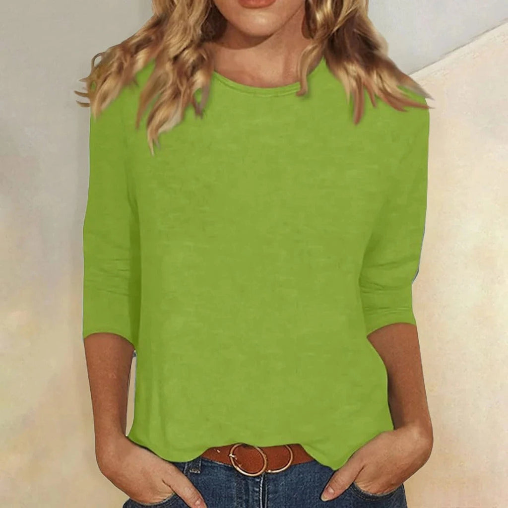 Woman wearing a green crew neck three-quarter sleeve top in a studio setting