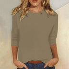 Woman wearing a khaki crew neck three-quarter sleeve top in a studio setting
