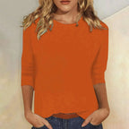 Woman wearing an orange crew neck three-quarter sleeve top in a studio setting