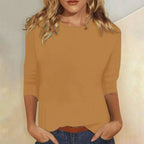 Woman wearing a brown crew neck three-quarter sleeve top in a studio setting