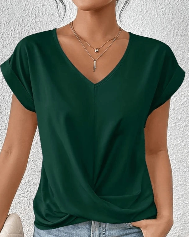 Woman wearing a green v-neck twist front short sleeve top in a studio setting
