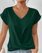 Woman wearing a green v-neck twist front short sleeve top in a studio setting