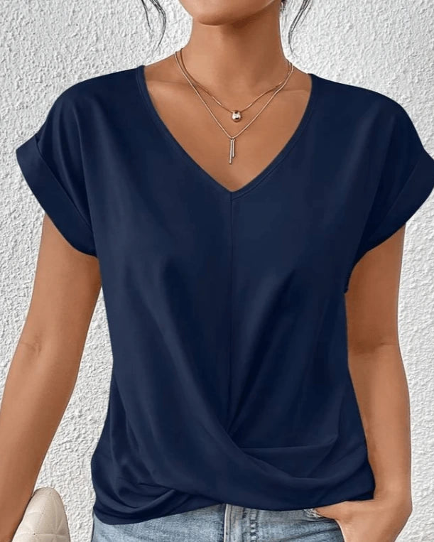 Woman wearing a navy v-neck twist front short sleeve top in a studio setting