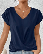 Woman wearing a navy v-neck twist front short sleeve top in a studio setting