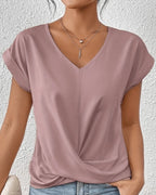 Woman wearing a pink v-neck twist front short sleeve top in a studio setting