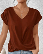 Woman wearing a brown v-neck twist front short sleeve top in a studio setting