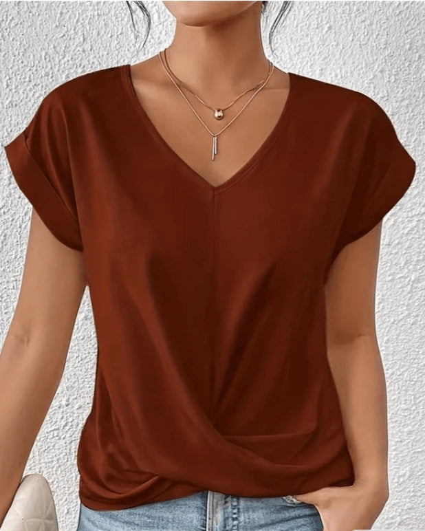 Woman wearing a brown v-neck twist front short sleeve top in a studio setting