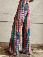 Woman wearing multicolor bohemian chic high-waisted wide-leg trousers with a geometric diamond print, back view