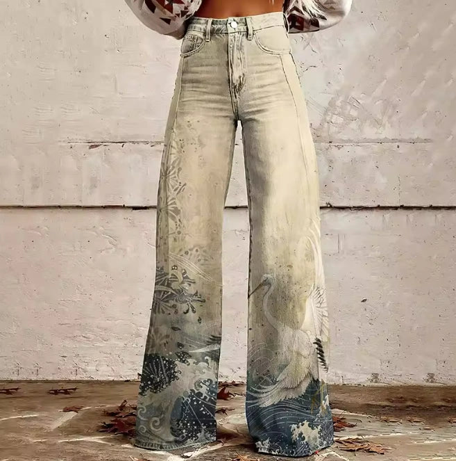 Close-up of cream bohemian chic tapered wide-leg trousers with a blue landscape print at the hem
