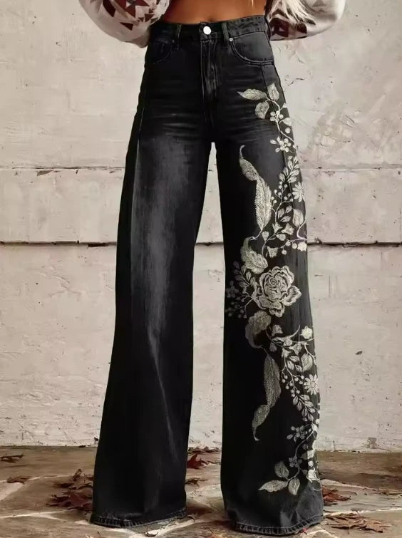 Close-up of black wide-leg trousers with a white floral embroidery print
