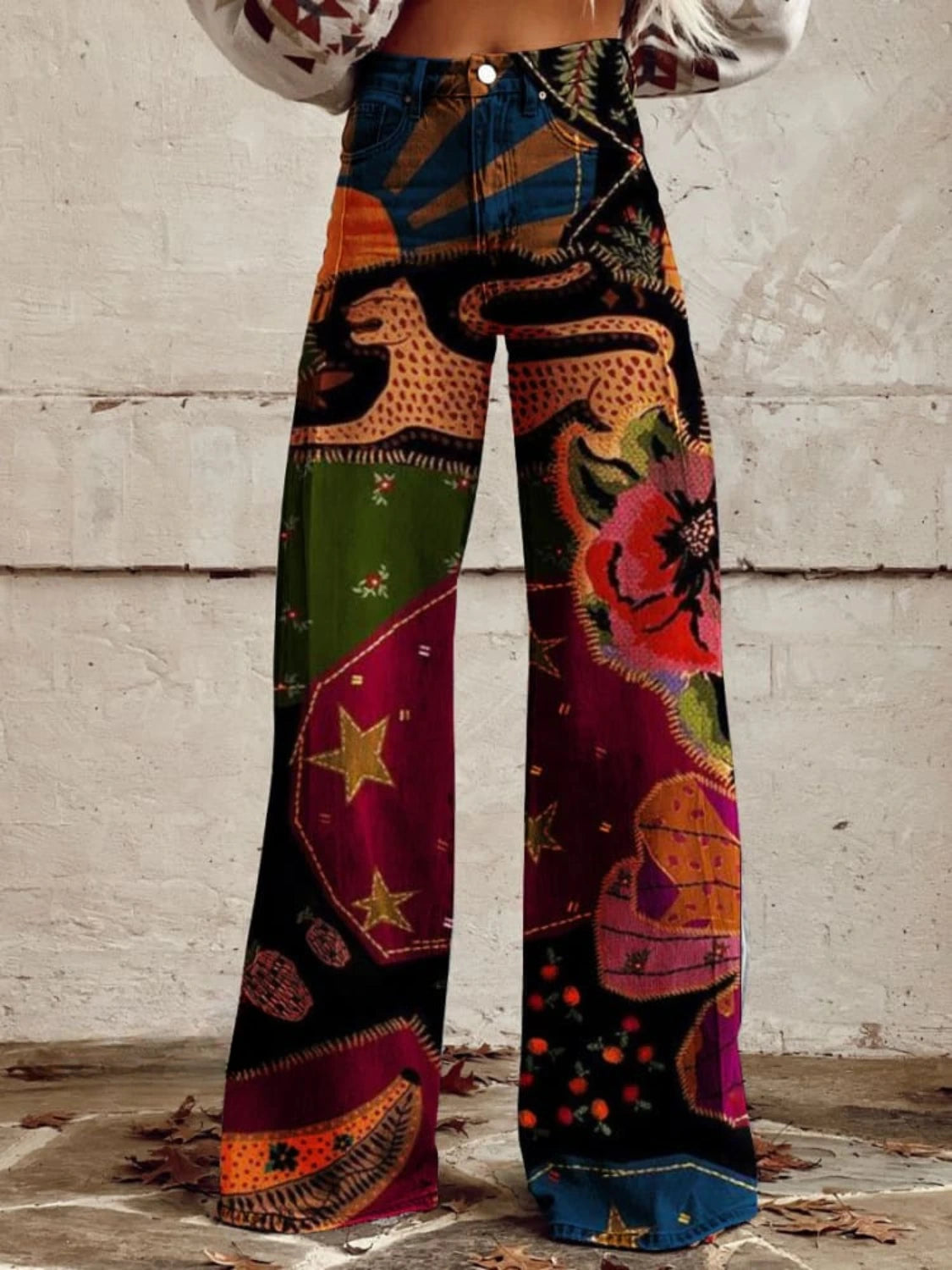 Woman wearing red and black bohemian print wide-leg trousers with gold star and floral details, front view