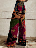 Woman wearing red and black bohemian print wide-leg trousers with gold star and floral details, side view