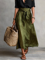 Woman wearing a black and olive green two-piece midi set, back view in a studio setting